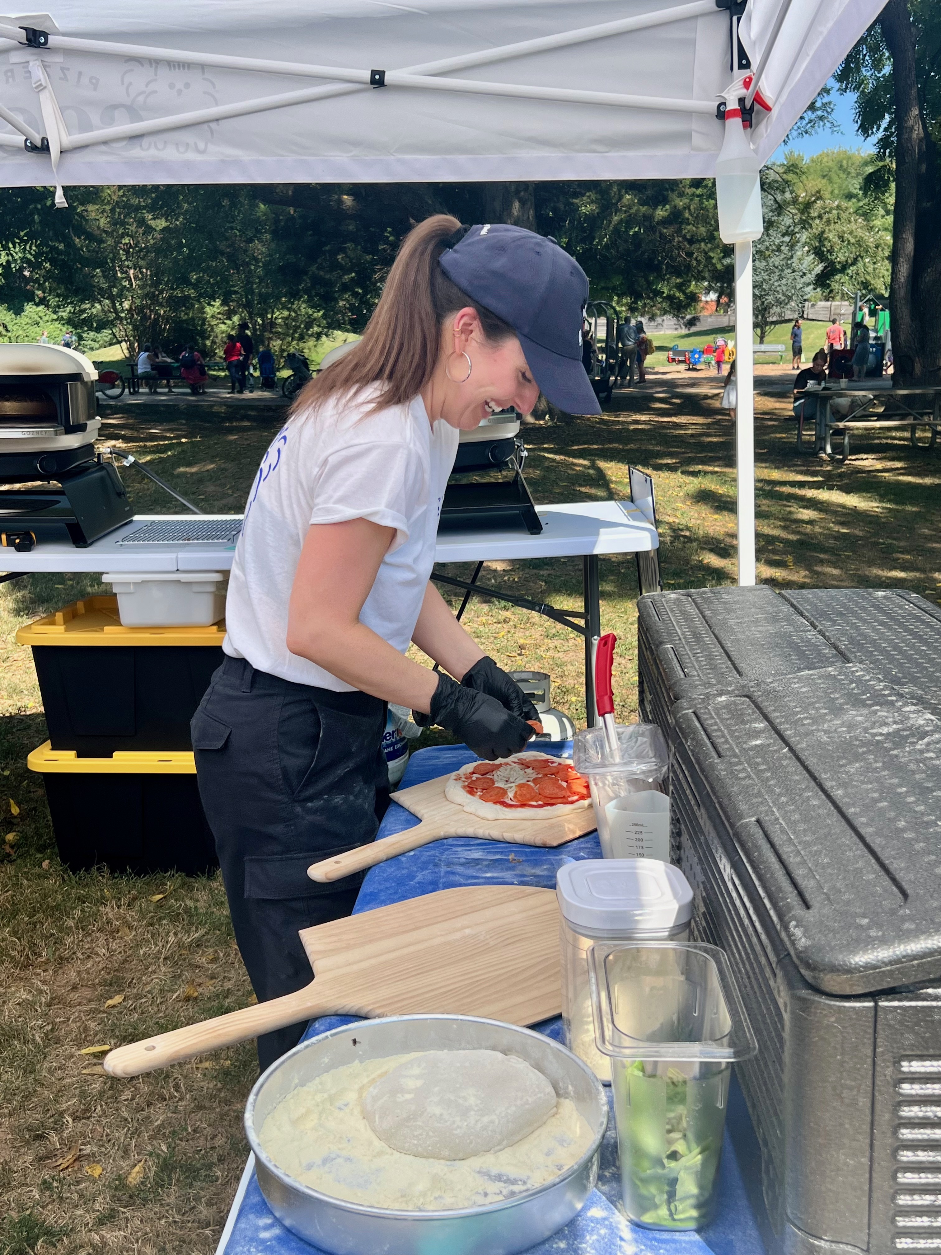 Co-owner of Pizzeria Coco having fun making a artisanal pepperoni pizza at an event.