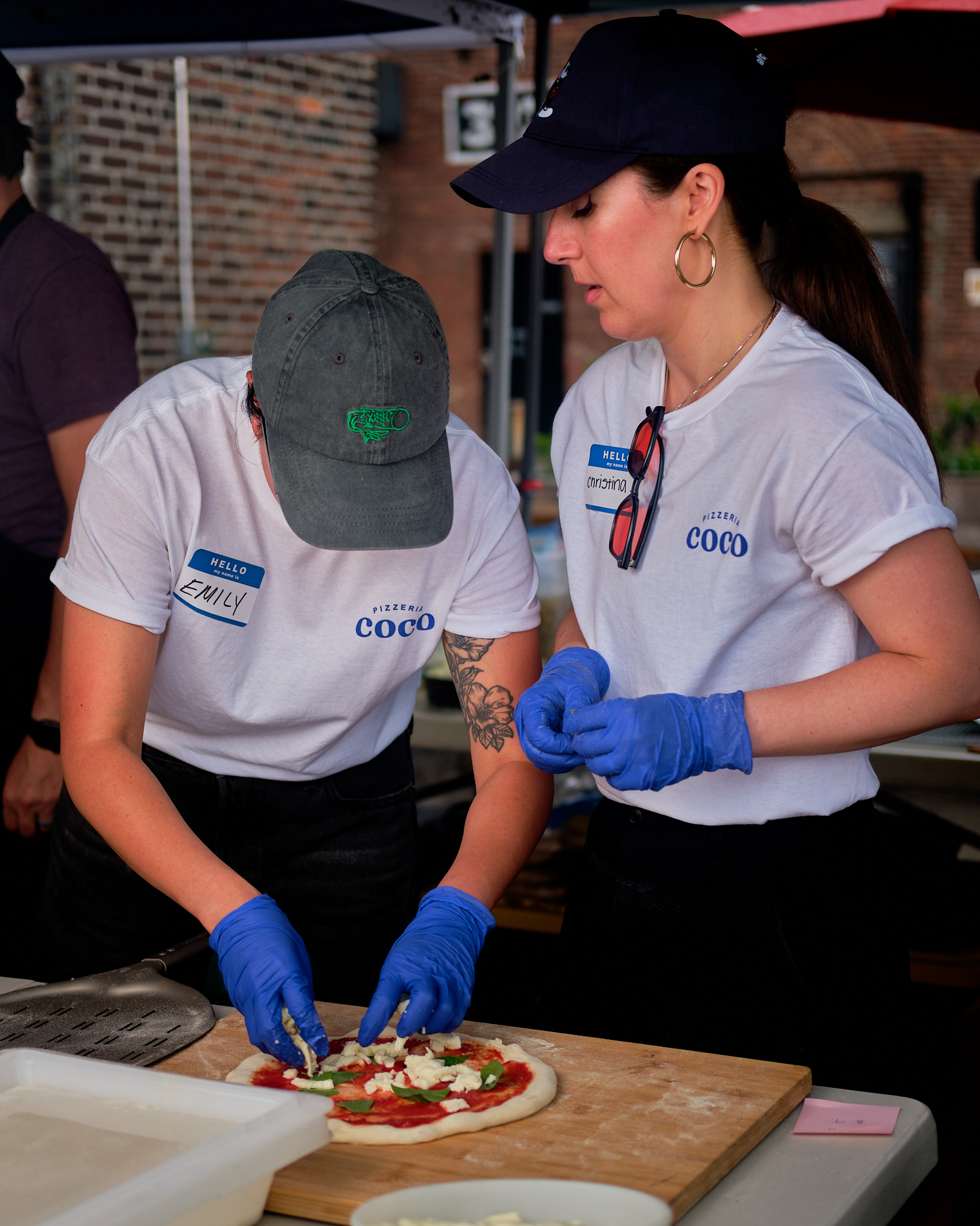 Two Pizzeria Coco owners preparing a artisanal Margherita pizza together at an event