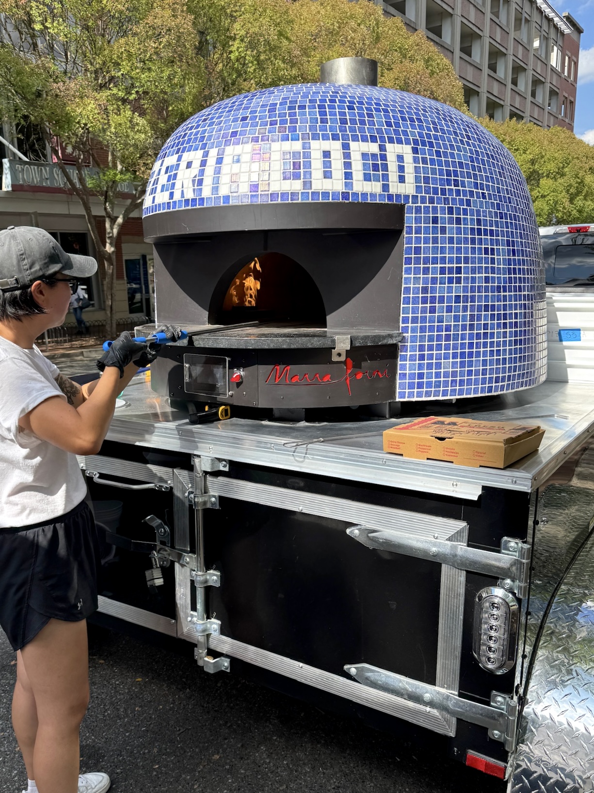 Pizzeria Coco team member cooking fresh pizza on a mobile brick oven dmv